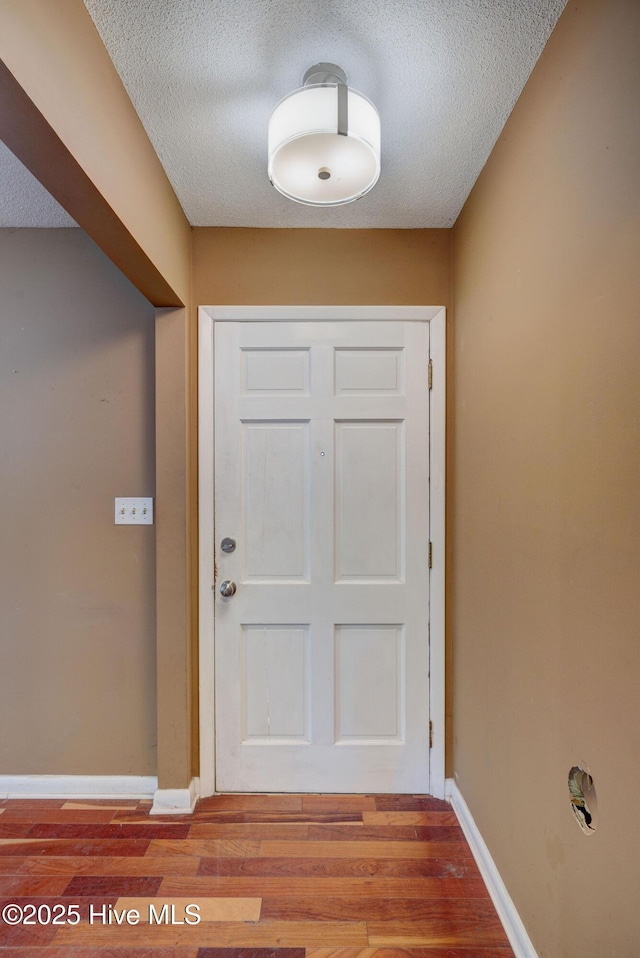 doorway with wood-type flooring and a textured ceiling