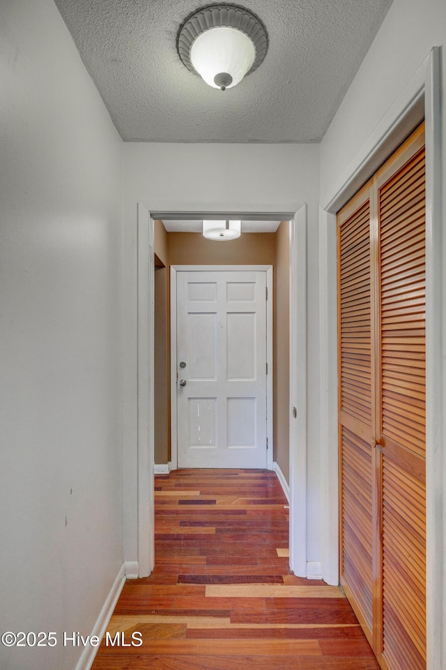 corridor with wood-type flooring and a textured ceiling