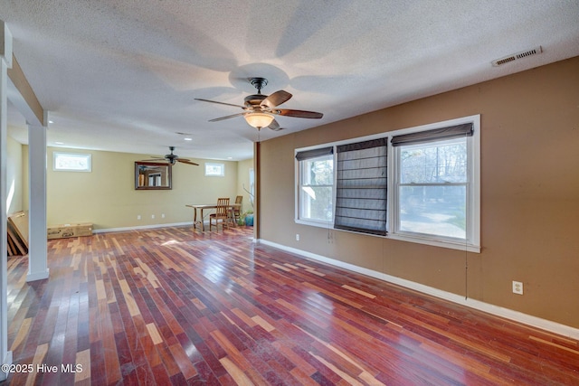 unfurnished room with wood-type flooring, a textured ceiling, and a wealth of natural light