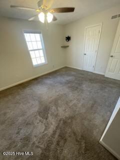 interior space with dark carpet and ceiling fan