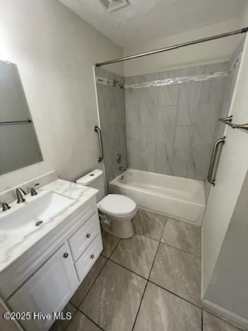 full bathroom with vanity, tiled shower / bath, a textured ceiling, and toilet