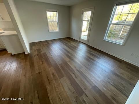 spare room with plenty of natural light and dark wood-type flooring