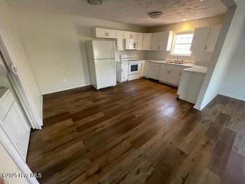 kitchen featuring white cabinetry, dark hardwood / wood-style flooring, sink, and white appliances