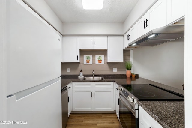 kitchen with sink, dark stone counters, white cabinets, and appliances with stainless steel finishes