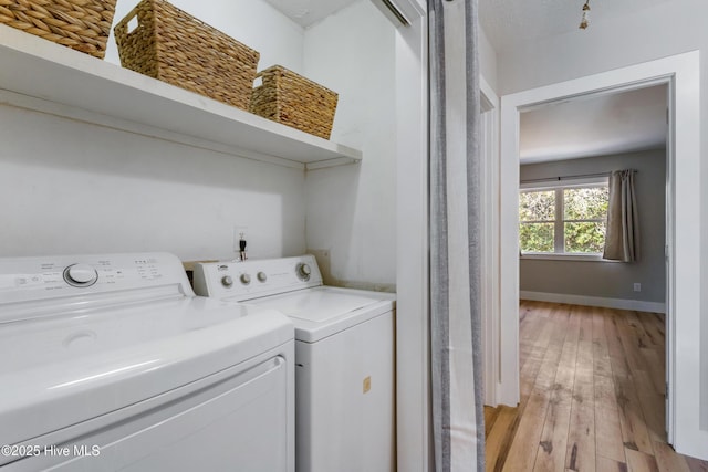 clothes washing area with washer and clothes dryer and light hardwood / wood-style floors