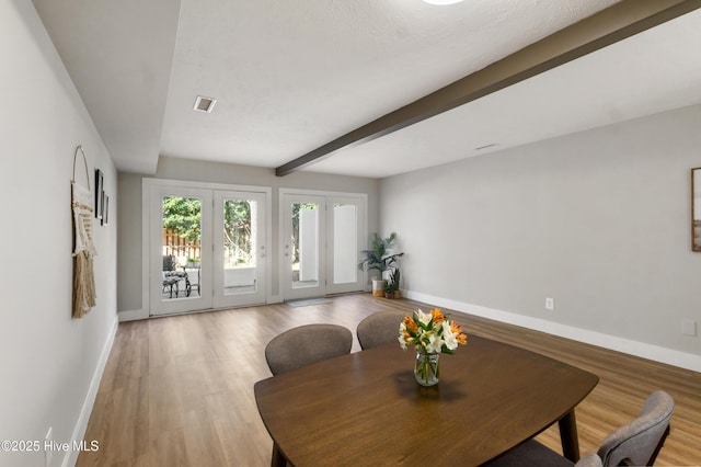 dining space featuring beam ceiling and light hardwood / wood-style floors