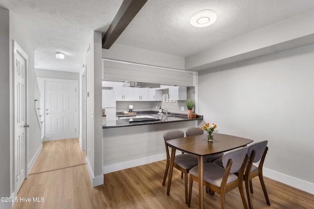 dining area featuring sink, light hardwood / wood-style floors, and a textured ceiling