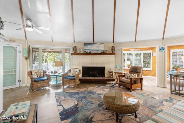 living area featuring a ceiling fan, lofted ceiling, a fireplace, and wood finished floors