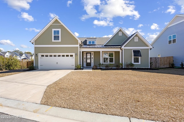 view of front facade with a standing seam roof, fence, metal roof, a garage, and driveway