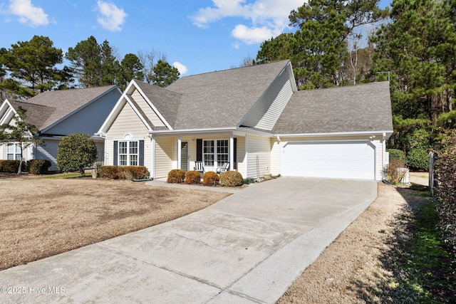 view of property with a garage, covered porch, and a front lawn