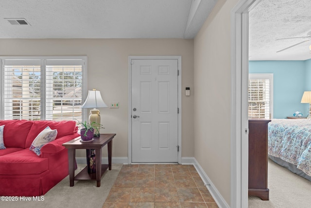 entrance foyer with light carpet, a textured ceiling, and ceiling fan