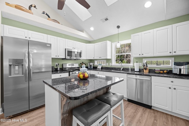 kitchen with stainless steel appliances, white cabinetry, hanging light fixtures, and a breakfast bar