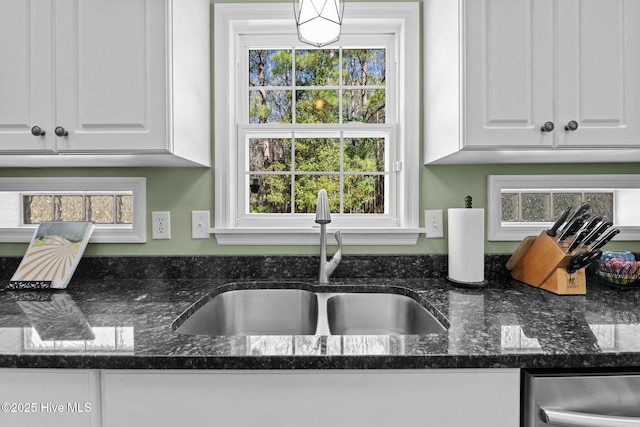 kitchen featuring white cabinetry, a healthy amount of sunlight, sink, and dark stone countertops