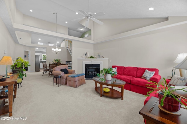 living room featuring carpet flooring, ceiling fan with notable chandelier, and high vaulted ceiling