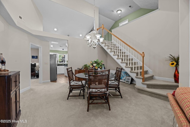 carpeted dining area with an inviting chandelier and high vaulted ceiling