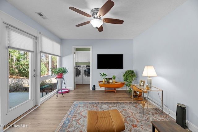 living room featuring ceiling fan, washing machine and clothes dryer, and light wood-type flooring