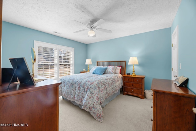 carpeted bedroom with ceiling fan and a textured ceiling