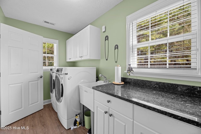 clothes washing area featuring cabinets, dark hardwood / wood-style floors, washer and dryer, and a textured ceiling