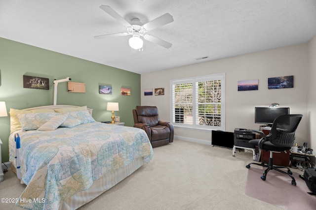 bedroom with ceiling fan, light colored carpet, and a textured ceiling