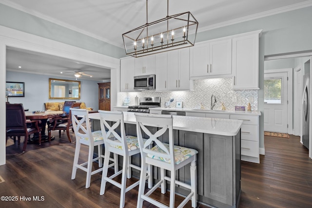 kitchen featuring appliances with stainless steel finishes, pendant lighting, sink, white cabinets, and a center island