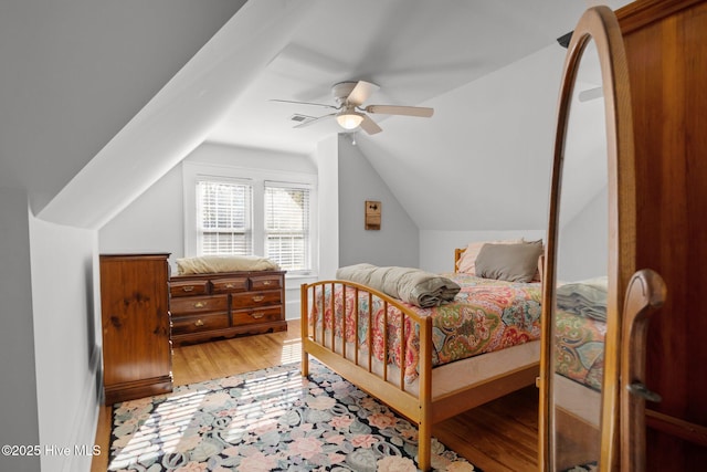 bedroom with ceiling fan, vaulted ceiling, and light hardwood / wood-style flooring