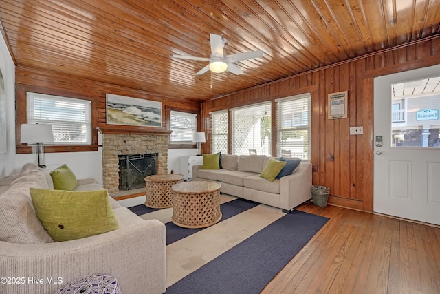 living room with ceiling fan, wooden ceiling, wooden walls, and light hardwood / wood-style flooring