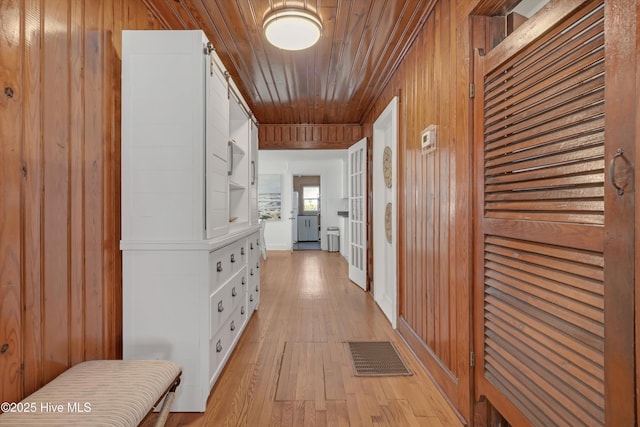 hall featuring wooden ceiling, light hardwood / wood-style flooring, and wood walls