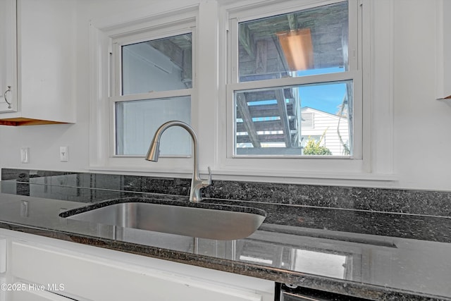 room details with white cabinetry, sink, and dark stone countertops