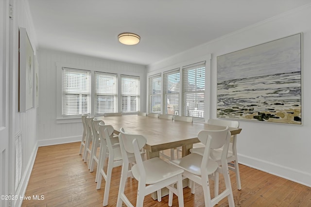 dining space with ornamental molding, a healthy amount of sunlight, and light hardwood / wood-style flooring