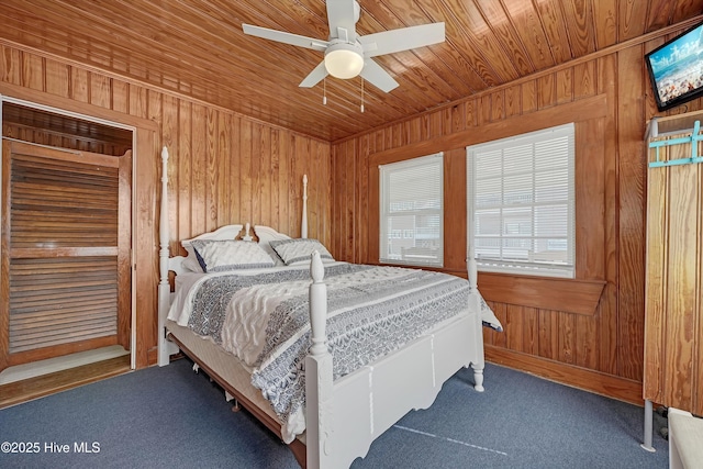 bedroom with ceiling fan, carpet floors, wood ceiling, and wooden walls