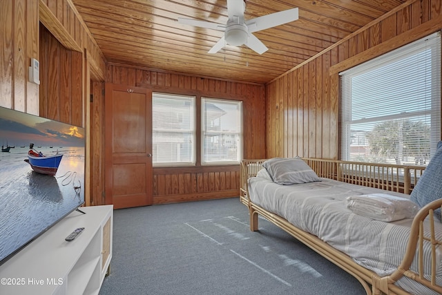 bedroom with carpet floors, wooden ceiling, ceiling fan, and wood walls