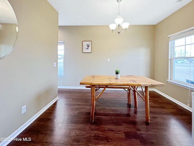 dining space with dark wood-type flooring and a notable chandelier