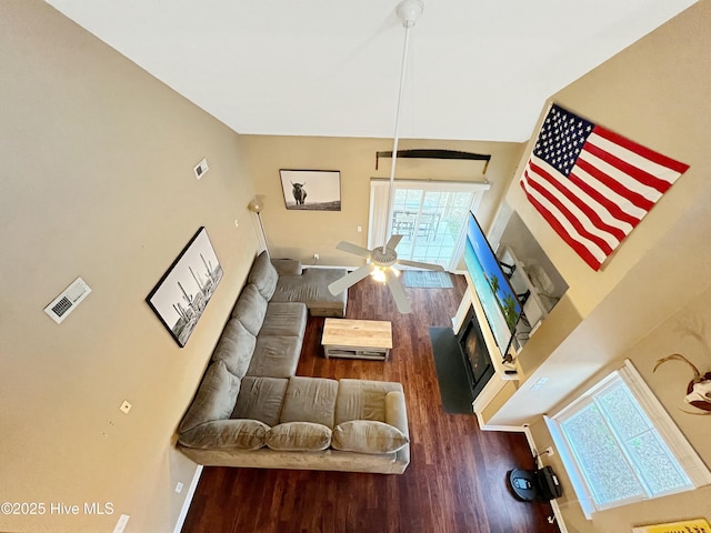 living room featuring hardwood / wood-style flooring, ceiling fan, and a towering ceiling