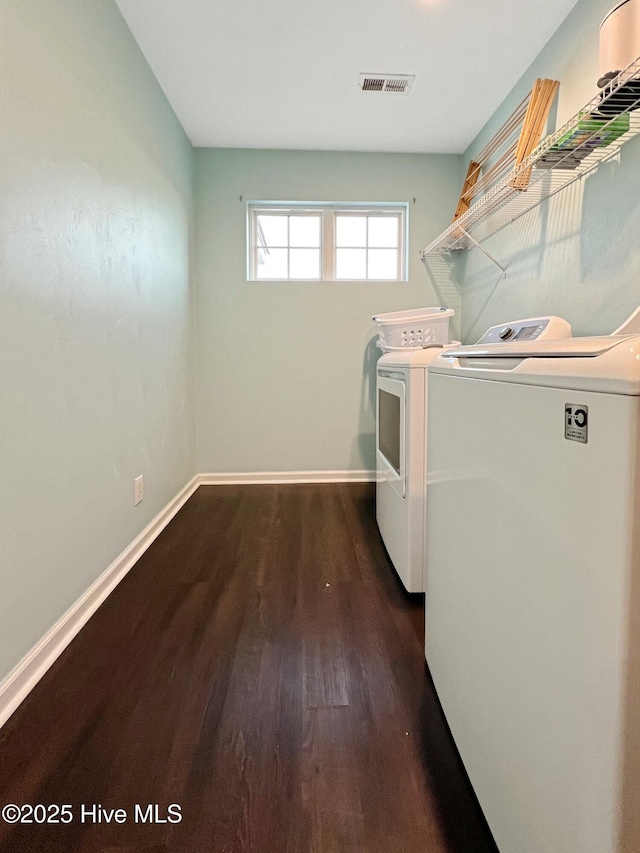 clothes washing area featuring washing machine and clothes dryer and dark hardwood / wood-style flooring