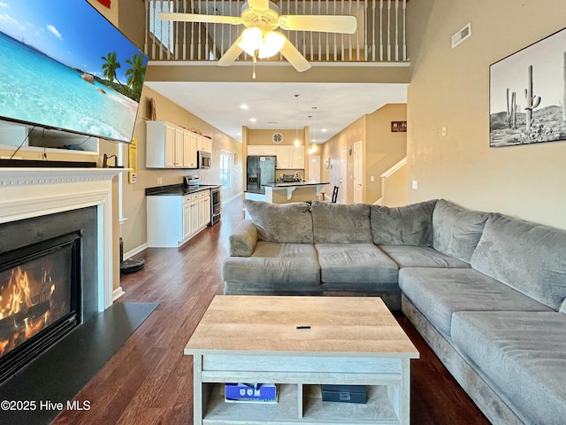 living room with a high ceiling, dark hardwood / wood-style floors, and ceiling fan