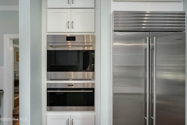 kitchen with crown molding, appliances with stainless steel finishes, and white cabinets