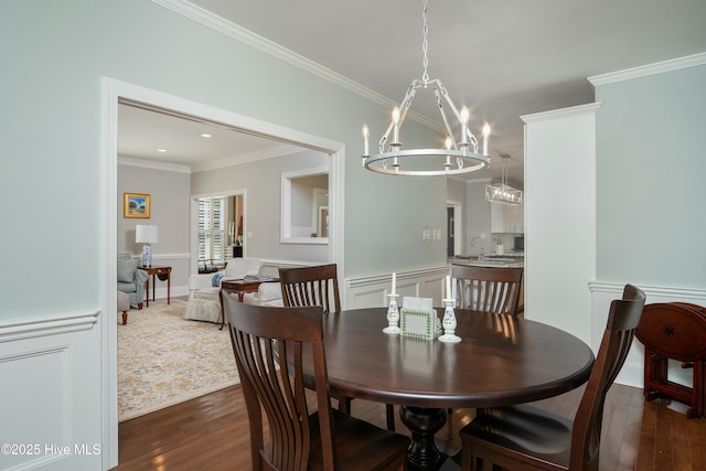 dining space with dark wood-type flooring, ornamental molding, and an inviting chandelier