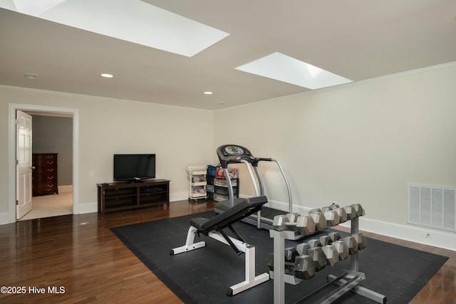 exercise area with hardwood / wood-style flooring, crown molding, and a skylight