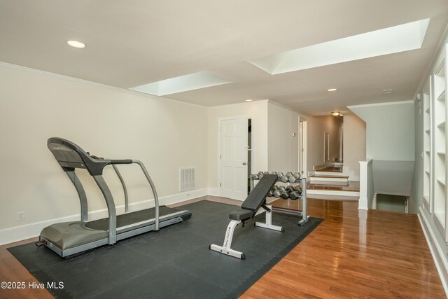 workout room with ornamental molding, dark hardwood / wood-style floors, and a skylight