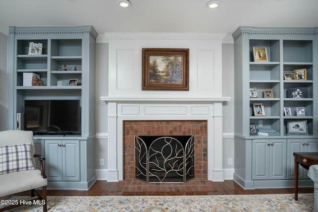 sitting room with dark hardwood / wood-style flooring, a brick fireplace, and built in shelves