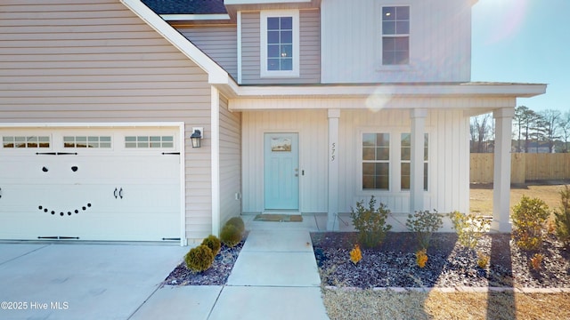 doorway to property featuring board and batten siding, fence, driveway, and covered porch