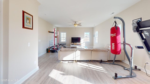 workout area featuring ceiling fan, baseboards, and wood finished floors