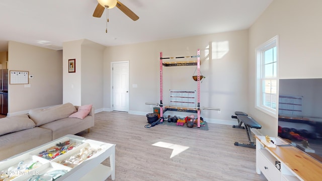 living room featuring ceiling fan, baseboards, and light wood finished floors