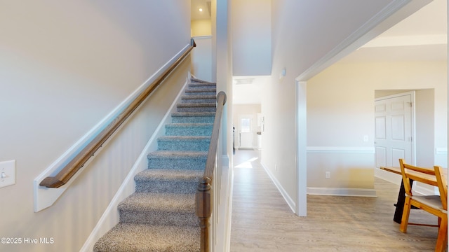 stairway featuring baseboards, wood finished floors, and visible vents
