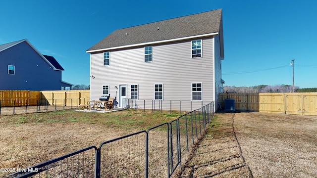 rear view of property with a fenced backyard, a yard, central AC, and a patio