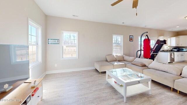 living room featuring light wood-type flooring, baseboards, a ceiling fan, and visible vents