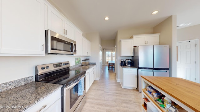 kitchen with light stone counters, light wood-style floors, white cabinetry, and appliances with stainless steel finishes