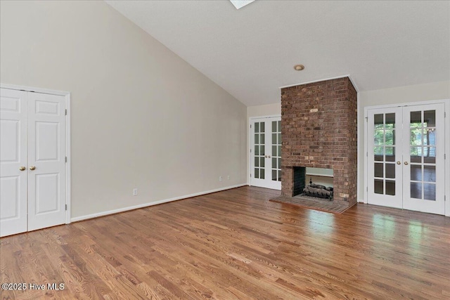 6 Elmhurst Pl, Pinehurst, NC 28374 - unfurnished living room featuring french doors, vaulted ceiling, wood finished floors, and a brick fireplace