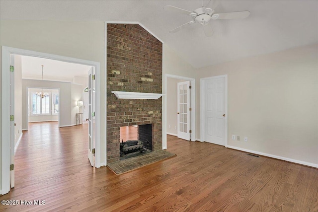 6 Elmhurst Pl, Pinehurst, NC 28374 - unfurnished living room with wood finished floors, a fireplace, a chandelier, a ceiling fan, and high vaulted ceiling