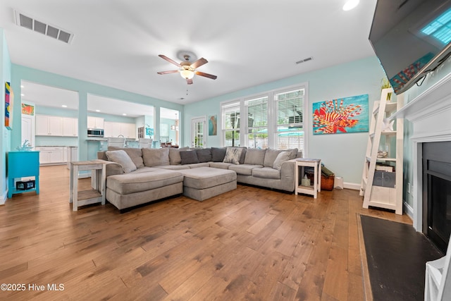 living room with ceiling fan and light hardwood / wood-style flooring